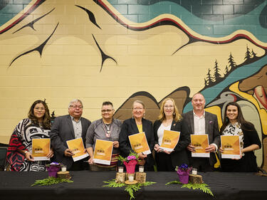 Group of Leaders from local First Nations, Metis community and district representatives, hold up their signed copies of the new enhancement agreement