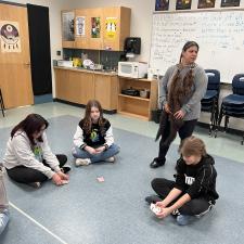 3 middle school students sitting on the floor as the secondary level ISW speaks