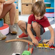 Young boy playing with a wooden train set.