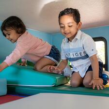 A young girl and boy playing in a soft play area within a transformed RV.